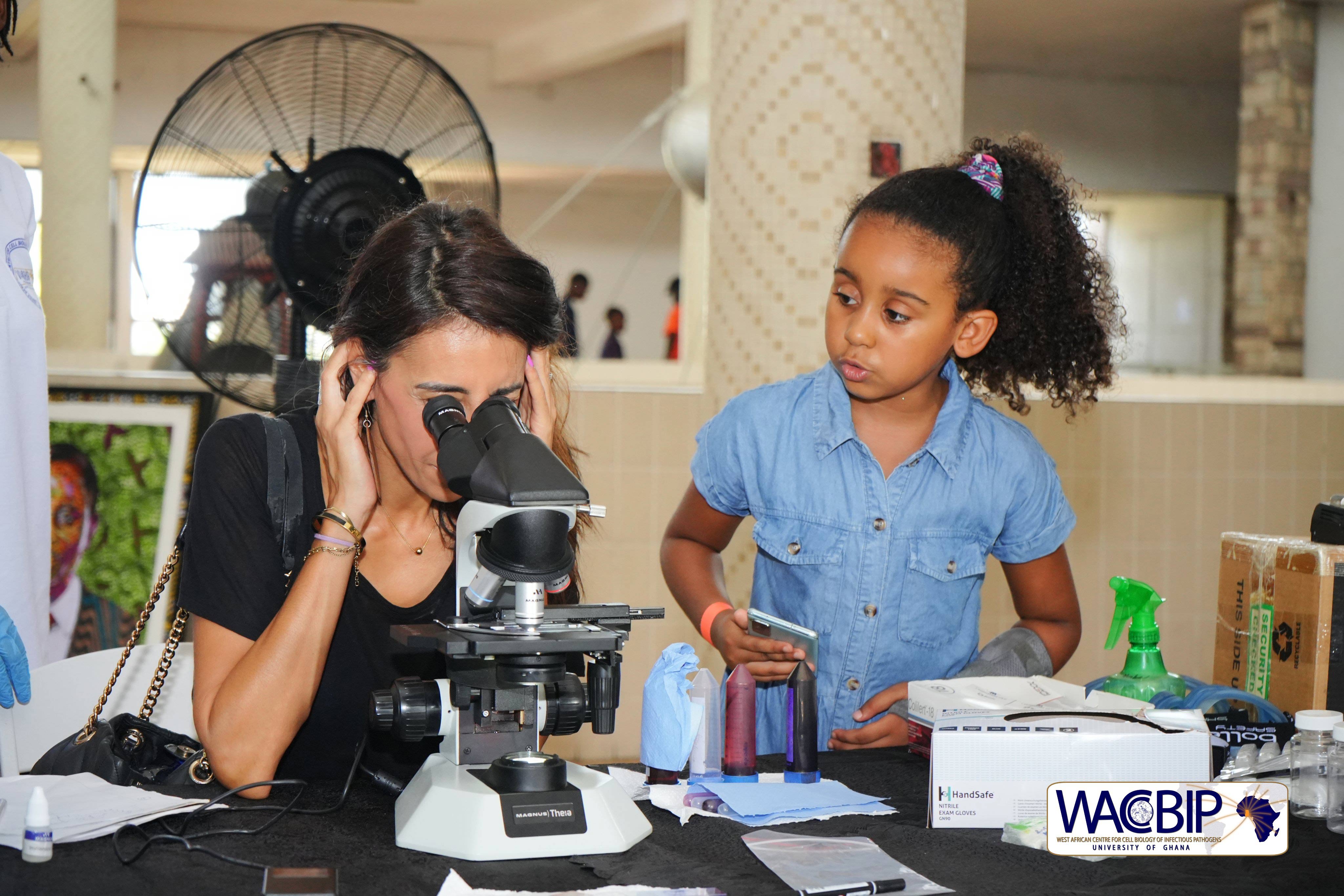Woman peering into microscope at science fair